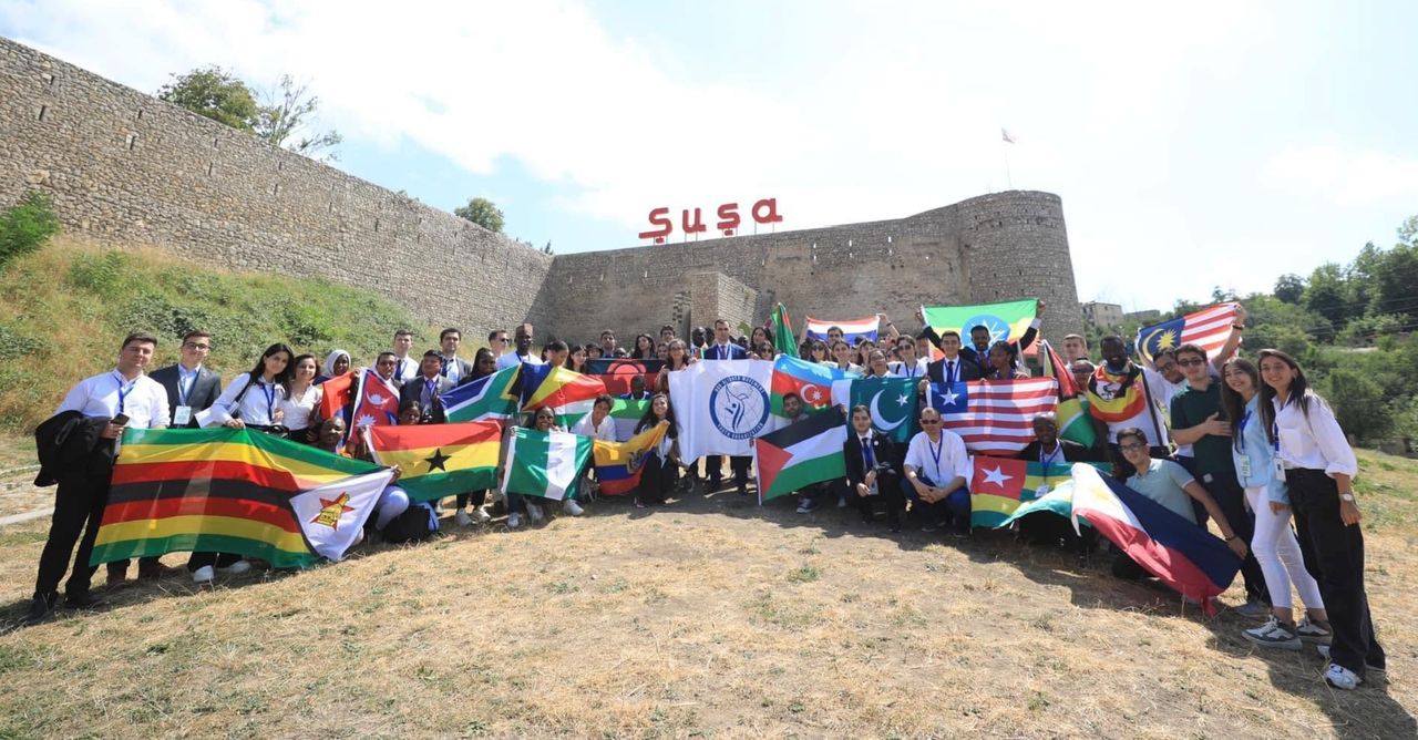 Summit participants holding national flags in front of the Shusha fortress wall