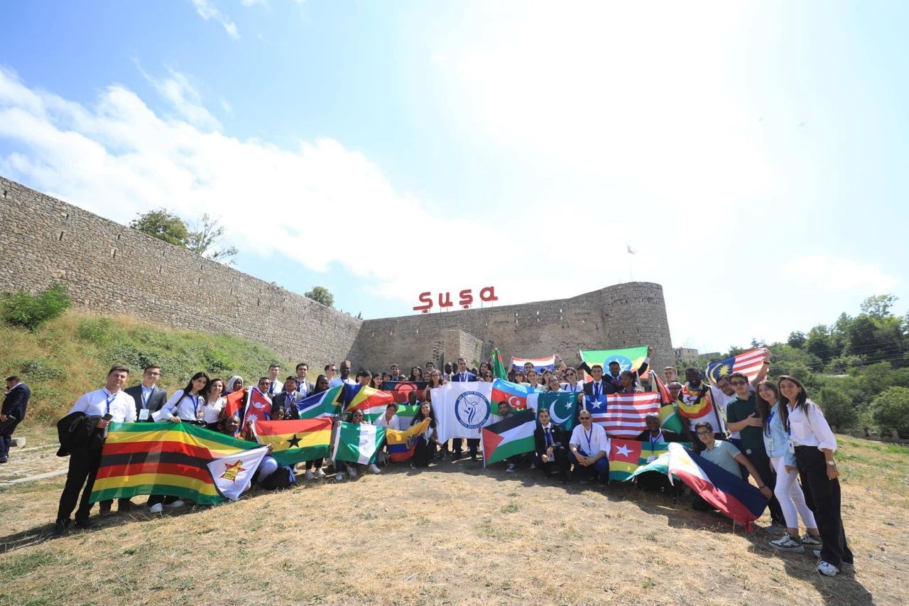 Summit participants holding national flags in front of the Shusha fortress wall