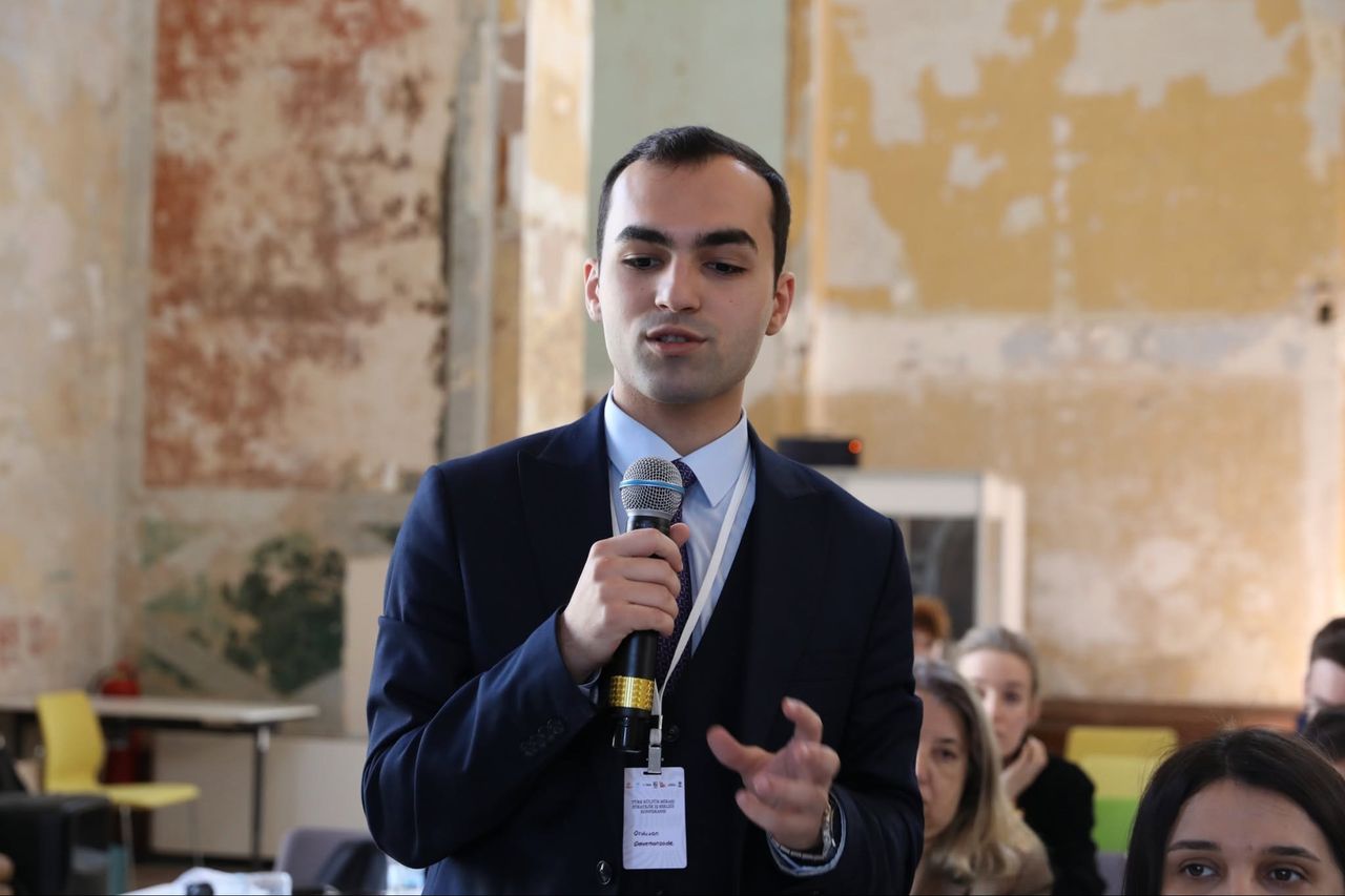 Ordukhan Gahramanzada presenting with a microphone at a conference